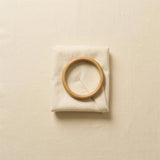 A folded baby garment beside a wooden ring, representing returns
